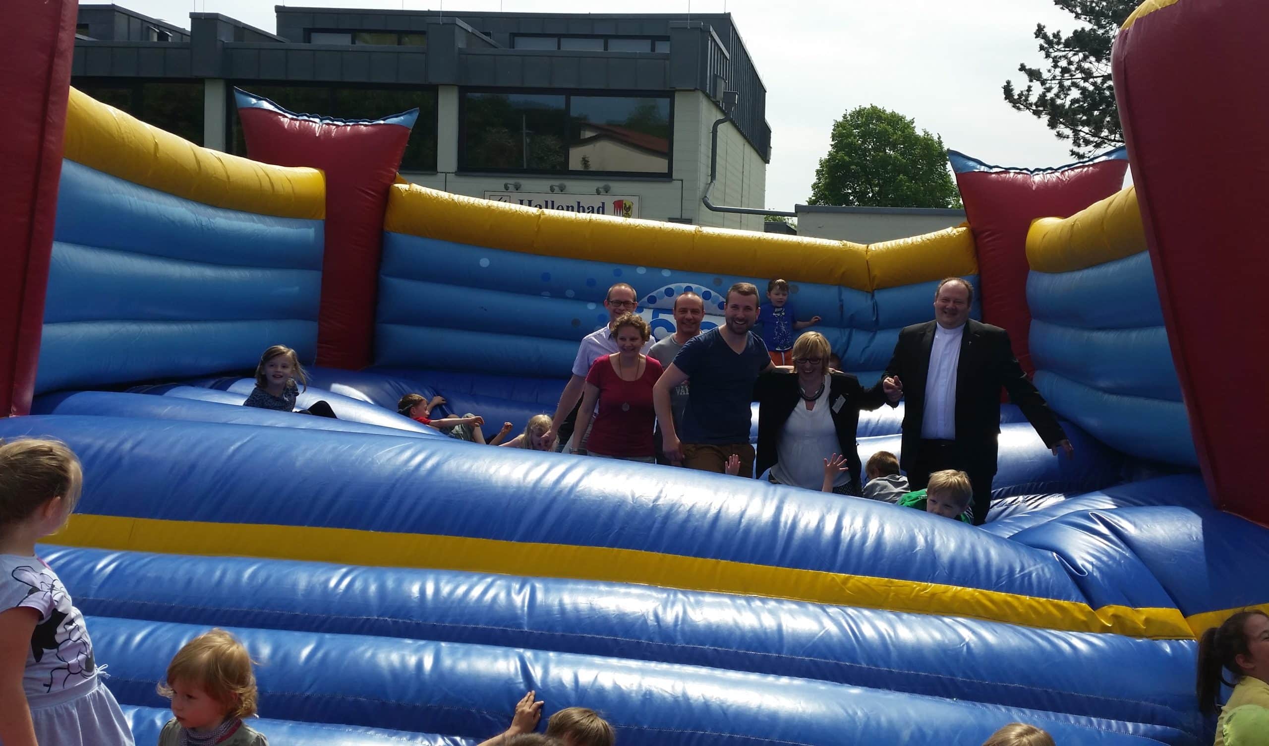 Kindergartenfest in Schonungen – Diakon, Bürgermeister und Kindergartenleitung auf der Hüpfburg